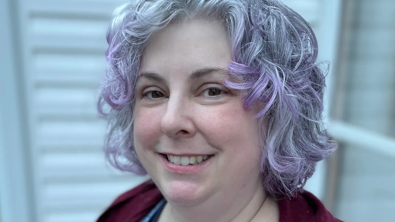 Amy Cogswell, a white woman with silver and violet hair smiles at the camera