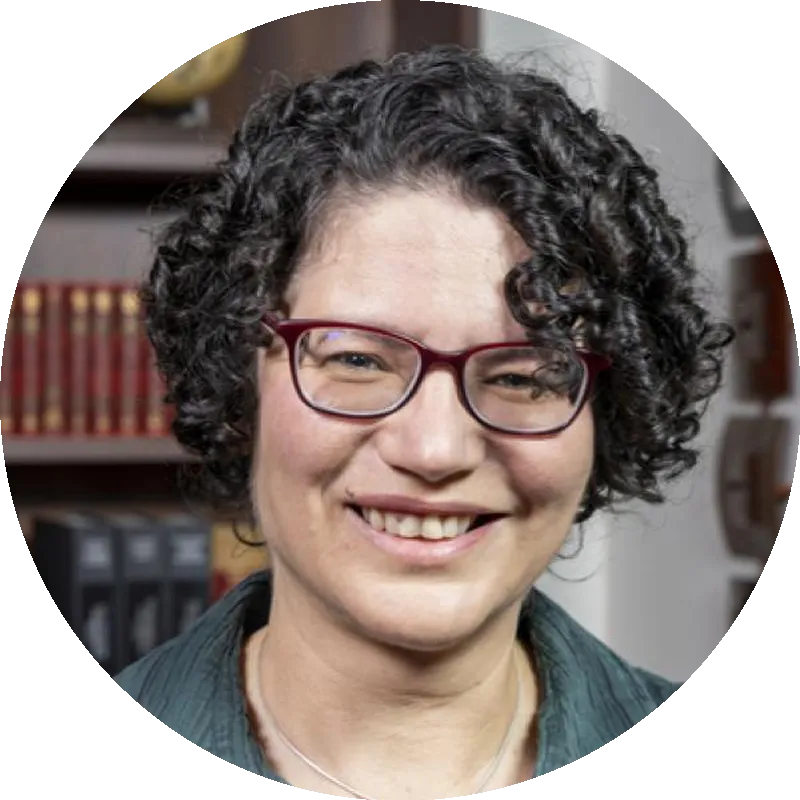 Headshot of Dr. Tanya Berger-Wolf, wearing glasses and a green top, smiling in front of bookshelves.